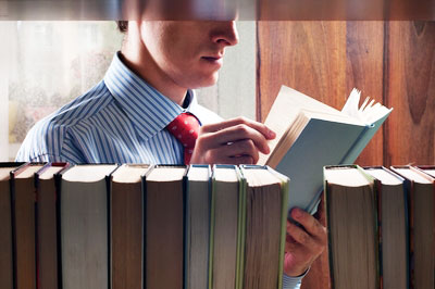 a man stands in a hospital library reading a book about his wife’s illness