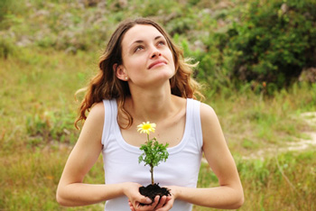 a woman holds a flower and looks up at sky