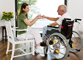 a patient advocate gives medicine to her elderly client, who is in a wheelchair