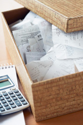 A Box with hospital bills inside, next to a calculator