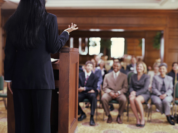 patient advocate stands at the podium at a health care conference